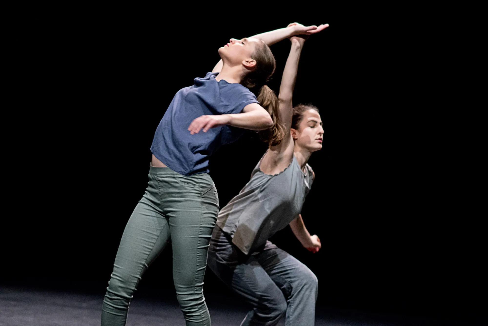 Two dancers, one arched back over the other, lit against black. Air Hunger by Hagit Yakira.