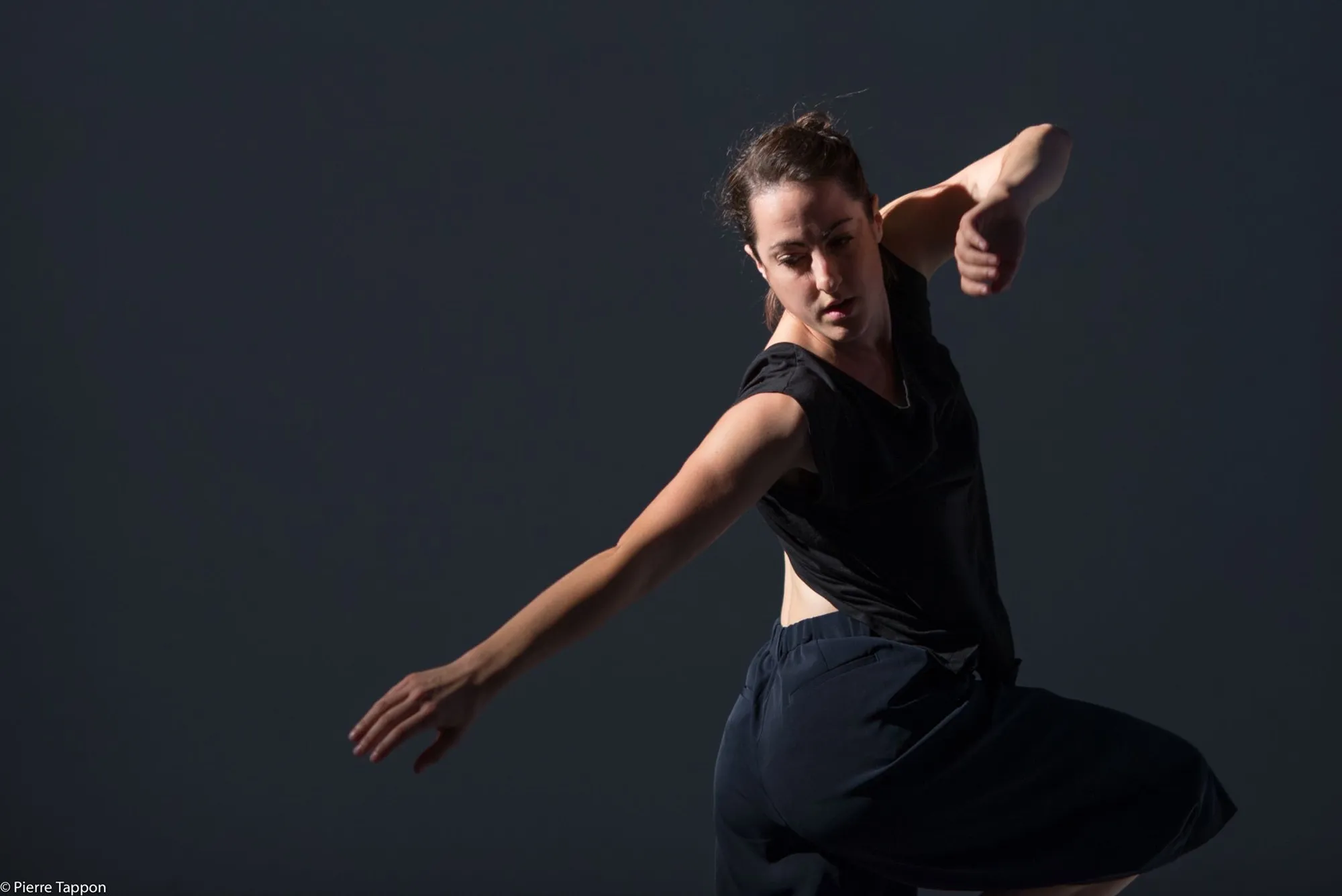 Sophie Arstall in a dark studio, one arm sweeping across her body