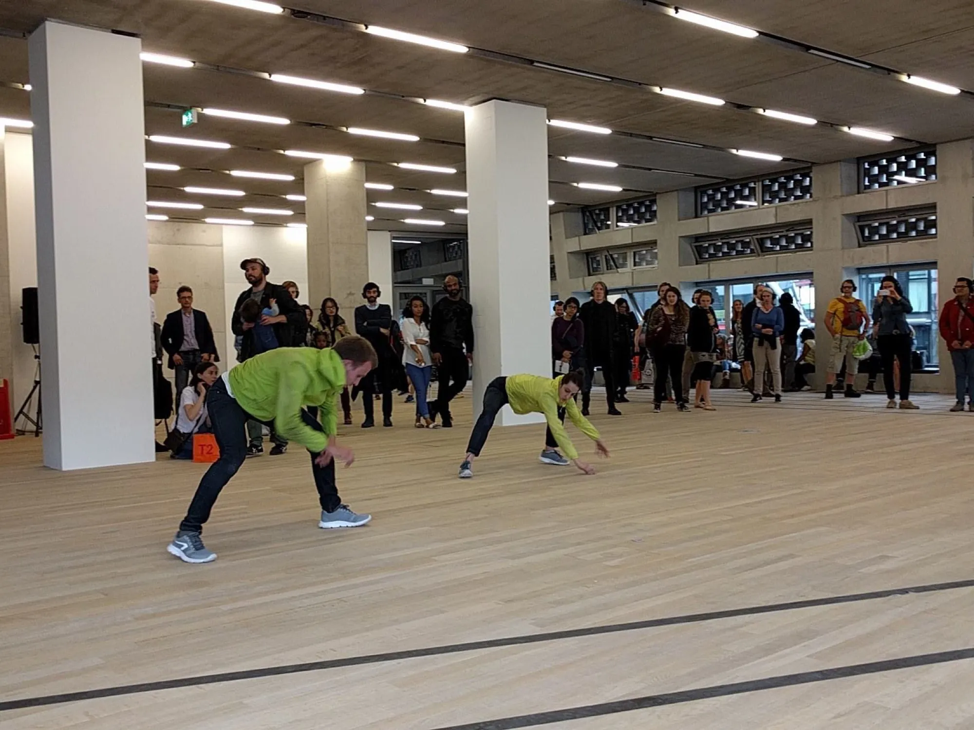 Participants moving across a wooden floor in a bright gallery space