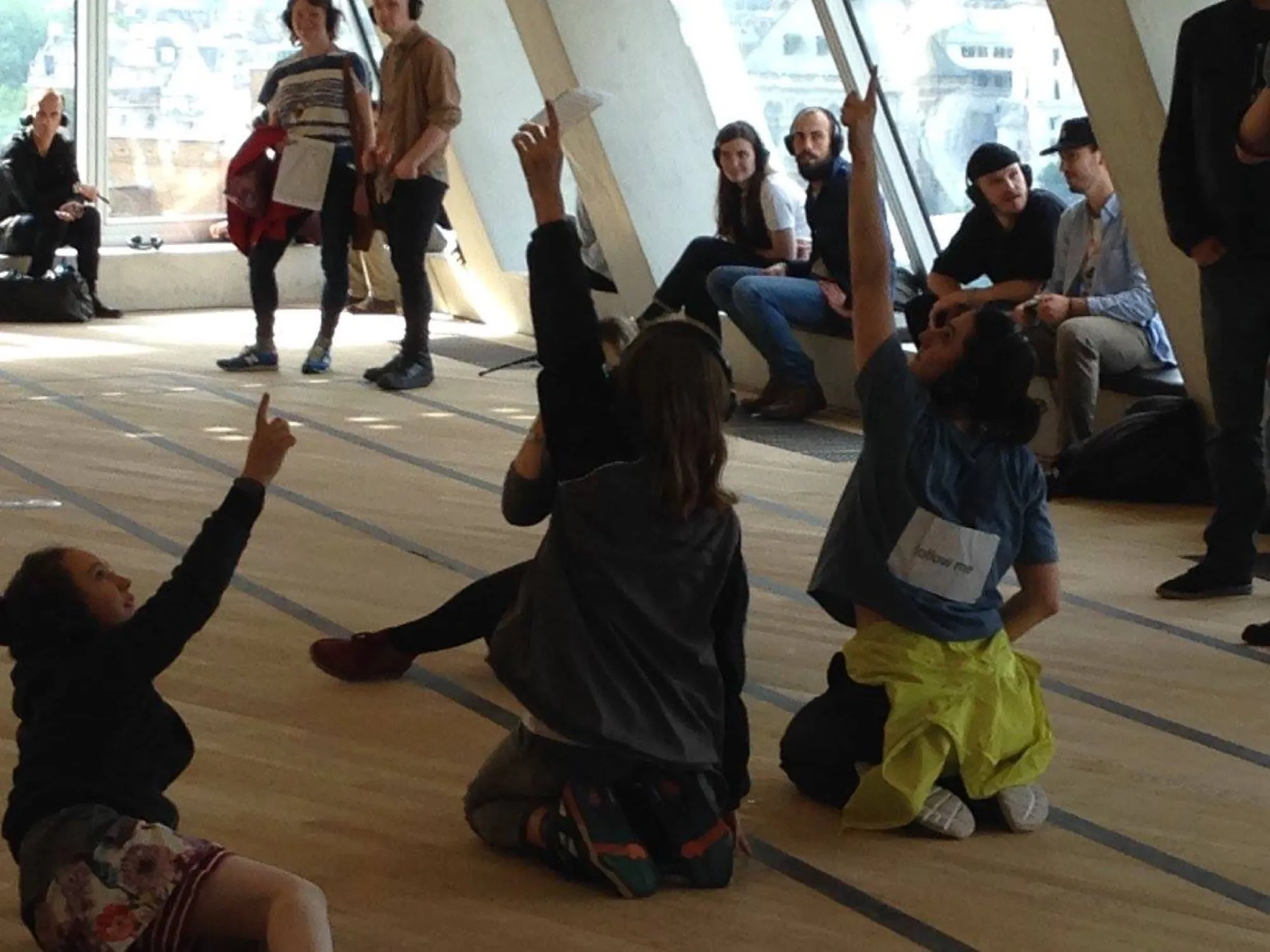 Participants sitting and reaching on a wooden floor at Tate Modern
